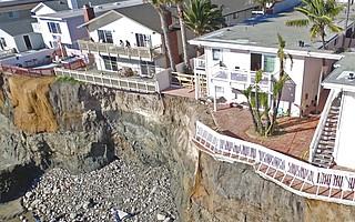 The owners of two apartment buildings on Del Playa Drive in Isla Vista — 6663, shown with a new chainlink fence blocking access to the balcony, and 6653, next door to the right — must come up with engineering solutions following Sunday’s cliff collapse, county officials say. James Gelb, owner of 6653 Del Playa, says he plans to demolish the two apartments on the west end of his building, shown here, and two on the east end. A portion of the balcony from 6653 Del Playa is lying below the rock slide.