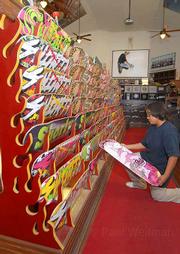 Assistant Manager Andy Lanes gets some air while Hanns Cholo checks out a Jesse Silvey-designed board at the Church of Skatan.