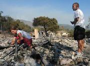 Dave Wolf, the men's and women's soccer coach at Westmont College, watches his wife Jill pick through the ashes of their home.
