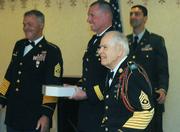 Retired Command Sergeant Major Robert Fortes (front) hands out ceremonial flags to returning soldiers with Brigadier General Beard and retired Command Sergeant Major Jonathan Church (left).