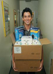 Patrick Krejdovsky, a physician assistant at the Eastside Neighborhood Clinic, holds one of the many boxes of medical supplies donated by DRI