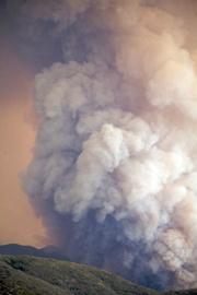 Huge cumulus cloud filled with smoke, ask and burning material rises more than a thousand feet as the fire advances towards the Sierra Madre Ridge just east of Timber Peak.