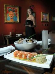 Milk & Honey server/bartender Jenna Allensworth shows some of the restaurant's tapas selections: Gambas Alcazar and Scallops Serrano.