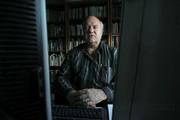Lee Campbell, backed by a wall of books and flanked by dual computer monitors, in his office