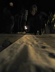Gatherers at the 11th annual Transgender Day of Remembrance candlelight memorial view a long list with names and photographs of victims of hate crimes, and descriptions of the way they died.