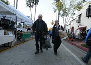 Ken Williams and Dr. Lynne Janhke walk through Tuesday's Farmers Market loaded with sweatshirts, rain ponchos, gloves, and socks.