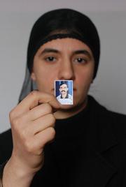 A few days after assailants killed his father, Rayan Nafa't Mikha was killed at his bicycle repair shop in Mosul, Iraq, in 2008. His widow holds his picture.
