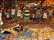 A street vendor sells cheap, last minute costume items to partiers during a late night bloco of Carnival.