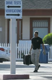 Santa Barbara Police officer Warren Holtke, working on detail with the Santa Barbara Sheriff's Bomb Squad, carries the suitcase deemed no longer a threat from the DMV.