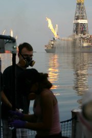 Research scientists aboard the RV Cape Hatteras at work. The oil capture rig, Discovery Enterprise, can be seen in the background.