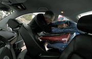Father Jon-Stephen Hedges loads his car with donated jackets that he will be distributed to those in need in the Isla Vista/ Goleta area