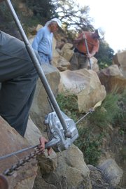 Ray Ford works a hand-cranked winch as Kalon Kelley and Rich Scholl move a boulder off the Baron Ranch Trail.