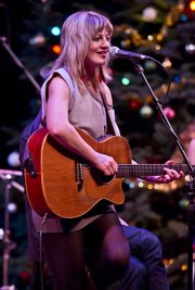 A casually clad Anaïs Mitchell leads her cast of characters and music-makers through a performance of her folk opera, <em>Hadestown</em>.