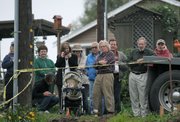 Art Gaspar (center with arms folded) watches with neighbors as construction crews work on his new modular home