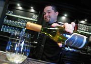 Jeffrey Parker, a bartender at the Hadsten House Inn and Spa, pours a glass of Bridlewood Chardonnay at the Hadsten House's restaurant during wine tasting hours.