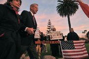 A couple attending the Dick Cheney talk last Saturday walk by protesters outside the Reagan Ranch Center