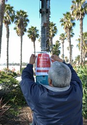 MTD worker posts a sign stating shuttle traffic will be temporarily discontinued on State Street below Gutierrez Street due to tsunami warnings.