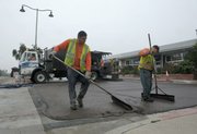 Pavement coating workers Cesar (left) and Danny finishing a slurry seal on the frontage road at Meigs Road and Cliff Drive