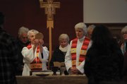Reverend Suzanne Dunn (left) consecrates the Holy Eucharist at Palm Sunday service as Reverend Love looks on. They invite members of the congregation to join them at the altar in saying the prayer converting the wafer and wine into the body and blood of Christ.