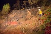While crews head uphill to douse hot spots, a City Fire inspector checks out the lower hillside to determine the cause of the fire.