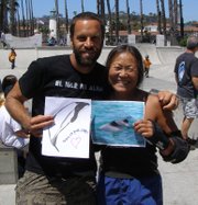 Jack Johnson and Peggy Oki, Origami Whales Project Founder & Director, hold a photo of a Maui's dolphin