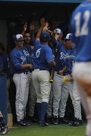 Robby Nesovic is greeted by his teammates in the dugout after doubling and scoring a run.