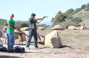 <b>BUDDIES WITH BULLETS:</b> Cade Wilson fires a revolver while Matt Struven loads a Mosin Nagant
at the Glass Factory.