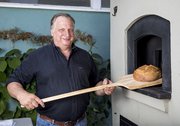 Santa Barbara Sourdough’s Stephen Meyer takes a loaf out of the woodfired oven at Goodland Kitchen