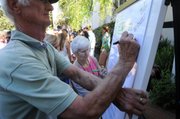 Reverend Jeannette Love (center), an associate pastor at the Catholic Church of the Beatitudes, signs the ECOFaith pledge