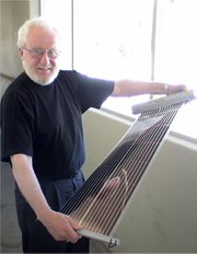 Dr. Alan Heeger holds a flexible plastic solar cell made with a roll-to-roll printing tool.