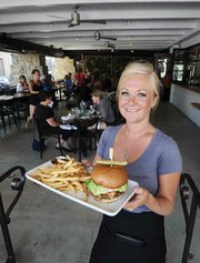 <b>SUB-$10 BURGER:</b> Benchmark Eatery's Allison Kearney presents the restaurant's affordable burger, which symbolizes the Bennett family's desire to serve all classes of Santa Barbarans.