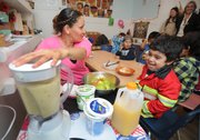 Maria Lopez (left) makes a smoothie with Storyteller Children's Center students. She says the kids will then bring donated fruit and good eating habits back home to their parents