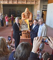 Peter Taksoe-Jensen (left), Rene Kaerskov (center), and Bent Olsen, of Olsen's Danish Village Bakery, pose with a cake and statue of Danish mythic hero Holger Danske.