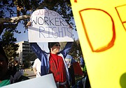 Jorge Manly-Gil holds a "Support Workers Rights" sign Friday evening during a later rally on the corner of Main and Broadway in Santa Maria.
