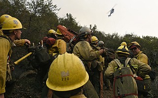 Members of Arroyo Grande Hotshots, Bend Oregon City firefighters, Santa Lucia Crew Seven and Vandenberg Hotshots working to cut a fire break, up steep terrain in Toro Canyon, welcome some water dropping helicopters after being 'bumped' back down the hill a bit 'into the black' burned area when flames shifted in their direction. (Dec. 12, 2017)