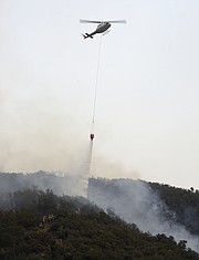 Water dropping helicopters, held back for most of the day due to poor visibility, give some much needed protection to firefighters working to cut a fire break, up steep terrain in Toro Canyon. (Dec. 12, 2017)