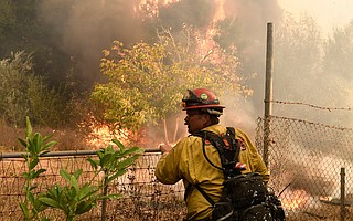 A Cal Fire firefighter keeps an eye on the edge of the Thomas Fire as it approaches evacuated structures behind him.