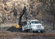County workers open up a debris basin to contain floodwaters in an area burned by the Thomas Fire.