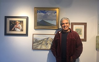Arturo Tello stands next to his painting of Montecito Peak, one of the many paintings donated to benefit Thomas Fire victims through a silent auction at the Porch gallery.