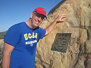 Berkeley "Augie" Johnson next to a plaque for his 19-year-old son, Nick, who died in a pool three years ago during swim training.