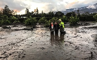 A firefighter helps two Montecito residents pick their way to Jameson Lane.